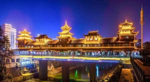 Vienna Hotel Hubei Enshi Railway Station في Longfengba: مبنى كبير أمامه جسر