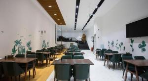a dining room with tables and chairs and a piano at Gya Hotel Beijing Shunyi Yanjing Bridge in Shunyi