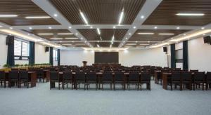 a large room with tables and chairs and a screen at Gya Hotel Beijing Shunyi Yanjing Bridge in Shunyi