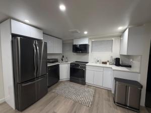 una cucina con mobili bianchi e un frigorifero in acciaio inossidabile di Pelham parkway North a Baychester 1 altra foto