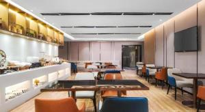 a restaurant with tables and chairs and a flat screen tv at Echarm Hotel Nanjing Expo Center Olympic East Metro Station in Nanjing