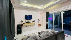 a living room with a couch and a tv at Cocktail Poolvilla Pattaya in Na Jomtien