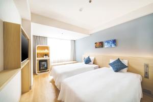 two beds in a room with a tv at 琉球オリオンホテル 那覇国際通り in Naha