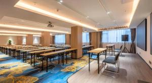 a conference room with tables and chairs and a screen at Echarm Hotel Guangzhou North Station Cultural Tourism City in Huadu