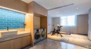 a bathroom with a sink and a washing machine at Echarm Hotel Guangzhou North Station Cultural Tourism City in Huadu