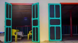 two open doors in a room with yellow chairs at Nomads Beach Resort in Clifton