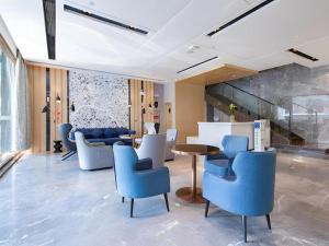 Echarm Hotel Wuhan Hankou Railway Station Zhuyeshan Metro Station في ووهان: ردهة مع كراسي زرقاء وطاولة