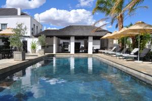 a swimming pool in front of a house at Swartberg Hotel, Cork Tree Collection in Prince Albert
