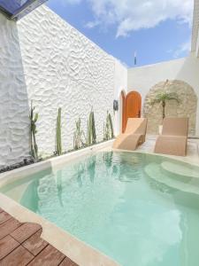 una piscina en una casa con sillas y cactus en Staycationku Premium Jogja Villas, en Beran-kidul