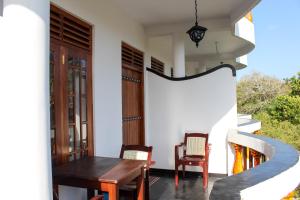 una casa con una mesa de madera y sillas en un porche en Orchid Rest, en Mirissa