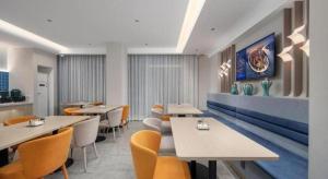 a restaurant with tables and chairs in a room at Jinjiang Inn Zhuhai Xiangzhou Qinglv Middle Road Theater in Zhuhai