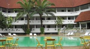 a hotel pool with chairs and tables and a building at Pailyn Hotel in Sukhothai