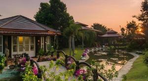 a garden with flowers in front of a house at De Bua Valley in Ban Kom