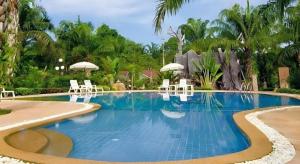 a pool with chairs and umbrellas in a resort at Nattha Waree Hot Spring Resort and Spa in Ban Hua Khuan