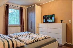a bedroom with a bed and a dresser with a tv at Unter den Kiefern 62 in Röbel