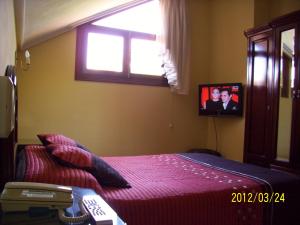 a bedroom with a bed with a tv on the wall at Hotel Noray in San Vicente de la Barquera