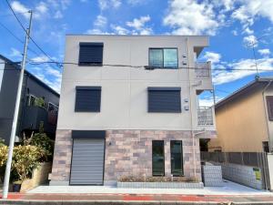ein weißes Haus mit blauen Fensterläden in der Unterkunft In time tokyo in Ichikawa