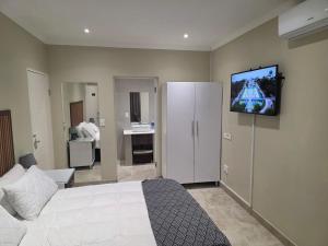 Un dormitorio con una cama y un televisor en la pared. en THE SEA BREEZE GUEST HOUSE & VENUE HIRE, 11 on SHELBOURNE, en Durban
