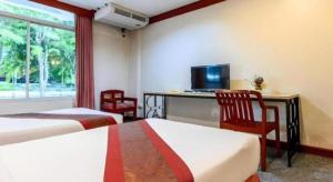 a hotel room with two beds and a desk and a television at Beverly Hill Park Hotel in Ban Pak Nam Pho