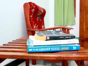 a stack of books sitting on a wooden chair at A One Calm Palace in Mirissa