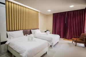 two beds in a hotel room with red curtains at Med Room Korat in Ban Pra Dok