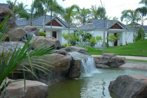a pond in front of a house with a waterfall at Forever Green Resort in Ấp Nhứt (1)