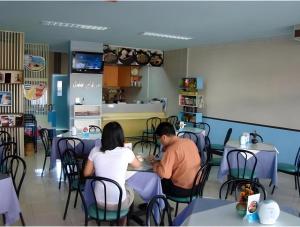 a man and woman sitting at tables in a restaurant at Grand Vissanu Hotel in Ban Pak Nam Pho