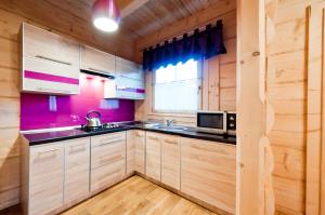 a small kitchen with wooden cabinets and a microwave at Domki Prokop in Ciche