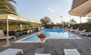 a swimming pool with lounge chairs and umbrellas at Hotel Bixio in Lido di Camaiore