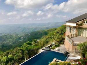 a villa with a swimming pool and mountains in the background at The Oriental Luxury Suites Tagaytay in Luksuhin