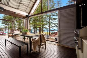 a room with a table and a bench on a deck at Luxury On The Bay 1 in Byron Bay
