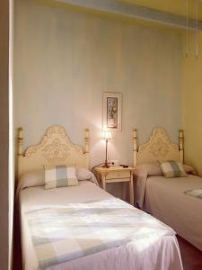 a bedroom with two beds and a table with a lamp at Molino La Boticaria in Marchena
