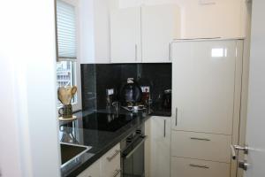 eine Küche mit weißen Schränken und einer schwarzen Arbeitsplatte in der Unterkunft Vlotho Apartment in Vlotho