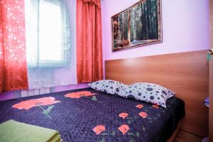 a bedroom with a bed with a floral bedspread and a window at Гостевой дом АГАТ in Omsk