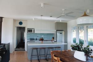 a kitchen with white cabinets and a table and chairs at The Yanakie House & Cabins in Yanakie