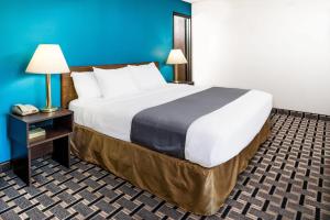 a large bed in a hotel room with a phone at Super 8 by Wyndham Lincoln West in Lincoln