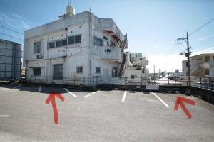a white building with red arrows in a parking lot at 2F - Vacation STAY 41669v in Okinawa City