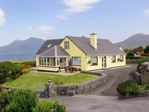 a yellow house with a stone wall at Seabreeze Junior Suite Renvyle in Renvyle