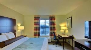 a hotel room with a bed and a desk and a television at AmericInn by Wyndham Oshkosh in Oshkosh