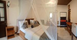 a bedroom with a white bed with a net at The Dream Homestay in Ella