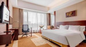 a hotel room with a large bed and a desk at Jiaxing Fortune Holiday Hotel in Jiaxing