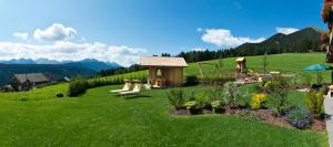 un jardin avec un banc et une aire de jeux sur une colline dans l'établissement Festnerhof, à Valle Di Casies