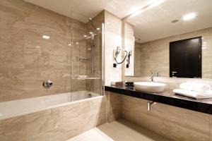 a bathroom with a tub and a sink and a shower at Hotel Victory in Brno