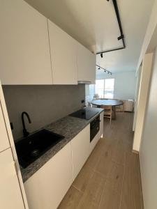 uma cozinha com armários brancos, um lavatório e uma mesa em Luxurious apartment with feet in the sea & city em Ostend
