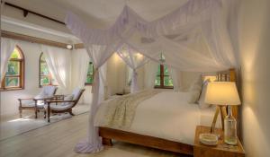um quarto com uma cama de dossel e uma mesa em Almanara Luxury Boutique Hotel and Villas em Praia de Diani