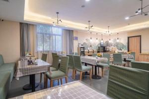 GreenTree Inn Wuxi Quanshan Center في ووشي: غرفة طعام مع طاولات وكراسي خضراء