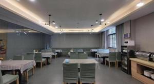 GreenTree Inn Wuxi Quanshan Center في ووشي: غرفة طعام مع طاولات وكراسي في غرفة