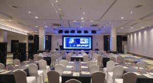 a large room with tables and white chairs and a screen at Huangshan Shuguang Yusong Hotel in Huangshan +146 photos