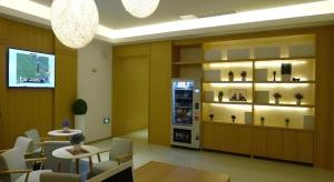 GreenTree Inn Shanghai Caohejing Development Zone Songjiang Park Jiuxin Road Business Hotel في Chunshen: غرفة بها طاولات وكراسي وعرض للمزهريات