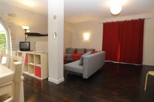 a living room with a couch and a red curtain at Appartement La Poulotte in Couchey